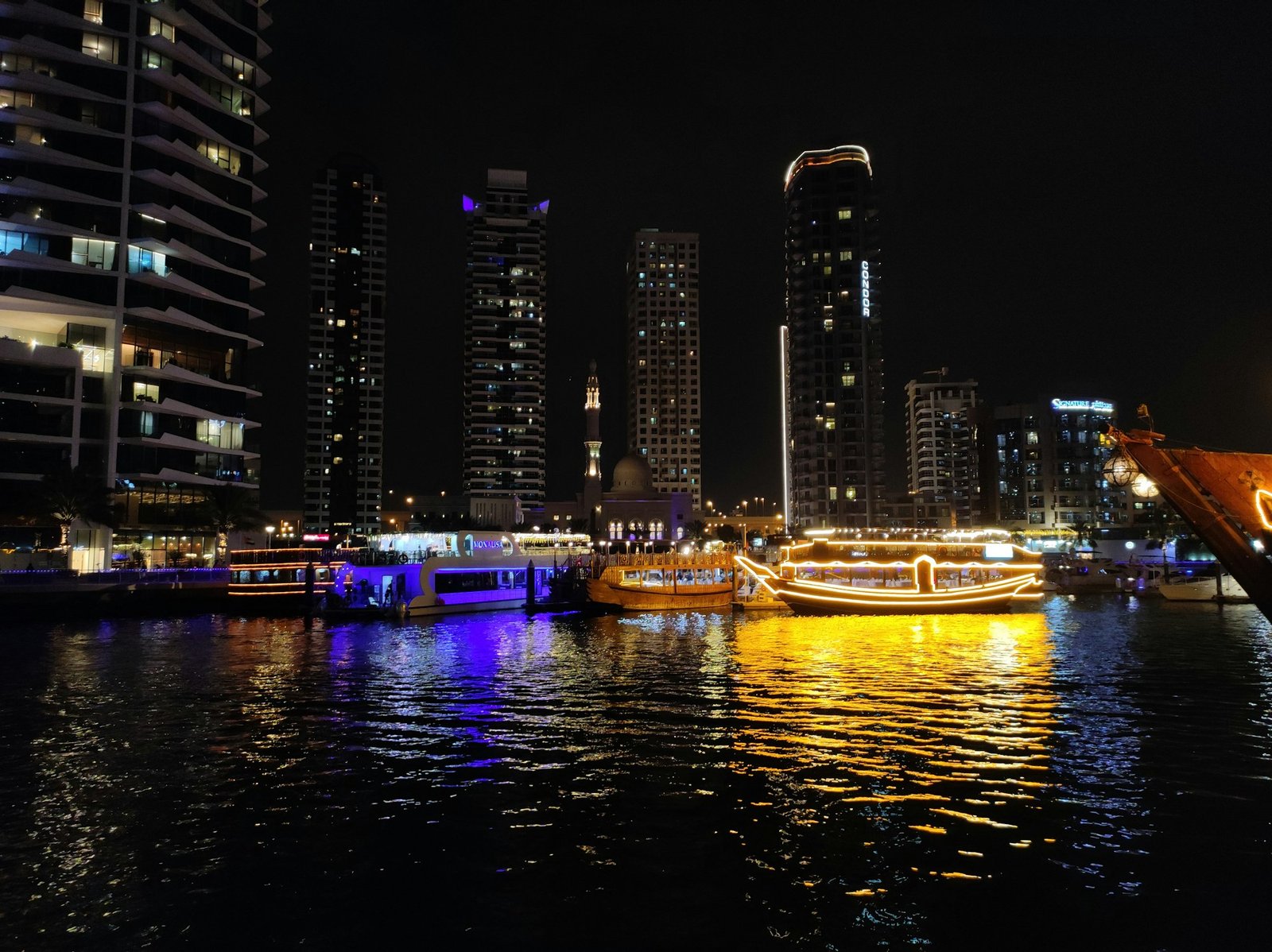 Dubai skyline at night with illuminated boats on the water
